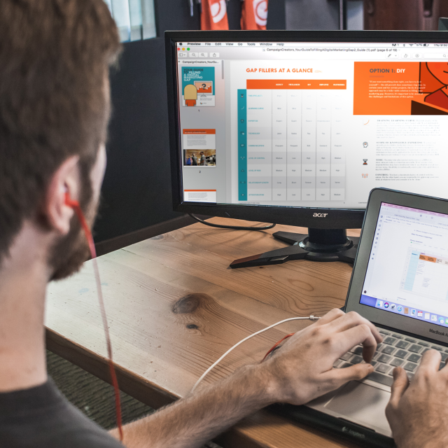 Man working on laptop and computer monitor