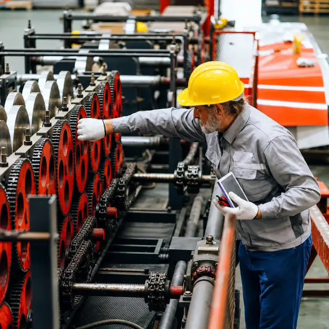 Industrial worker using a tablet to inspect manufacturing equipment.
