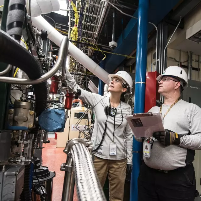 Man and woman in hardhats working on machinery 