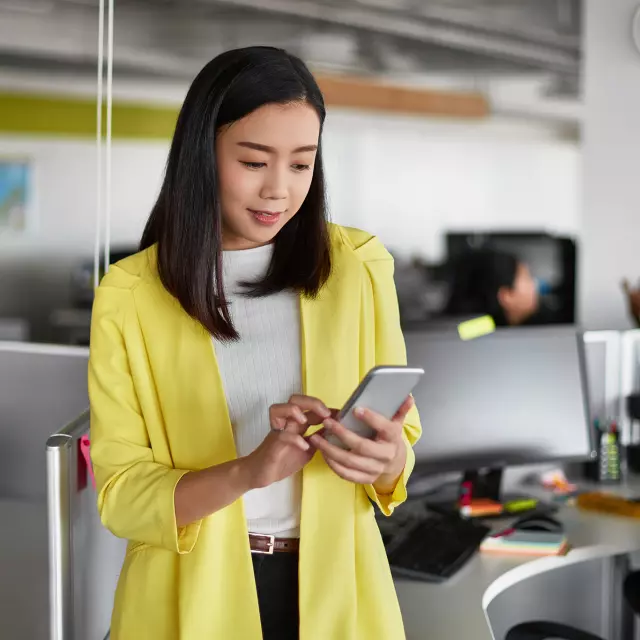 Woman in an office looking at her smartphone