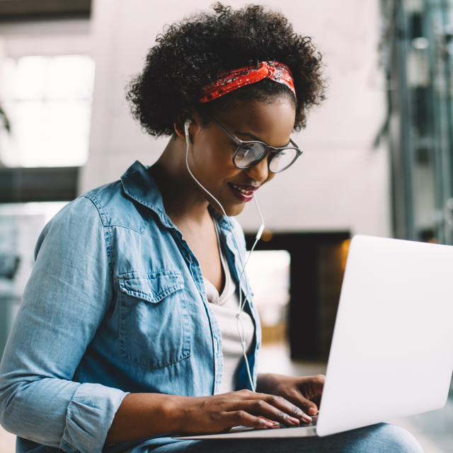 Woman with earbuds working on a laptop