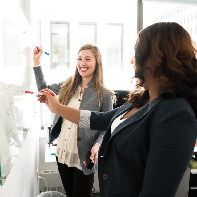 Two woman working together on a whiteboard