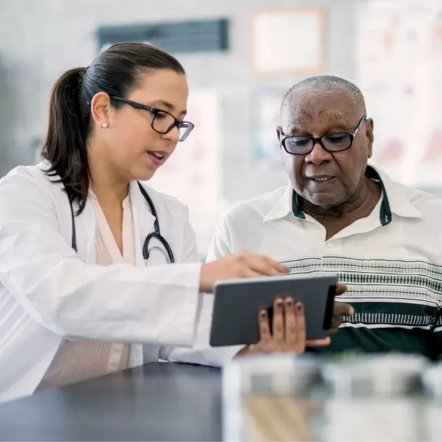 Nurse sitting next to man pointing at tablet