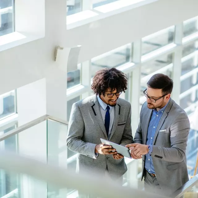 Two men reviewing contracts on a tablet