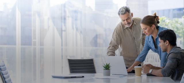 Coworkers standing around laptop