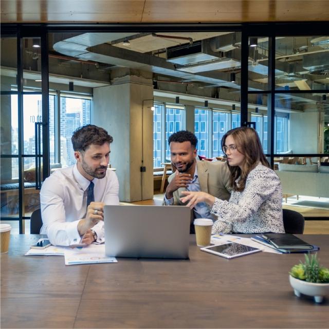 Three coworkers sitting at table around laptop