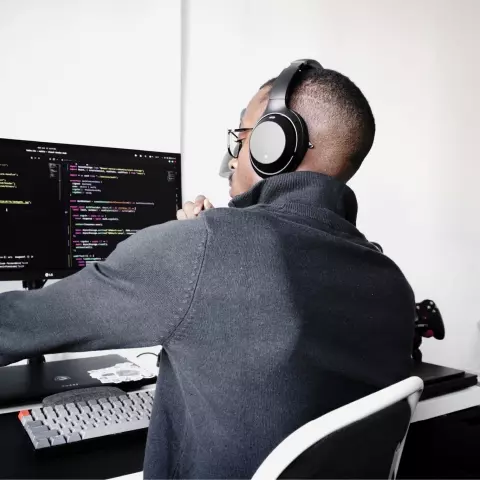 Man wearing headset looking at code on computer